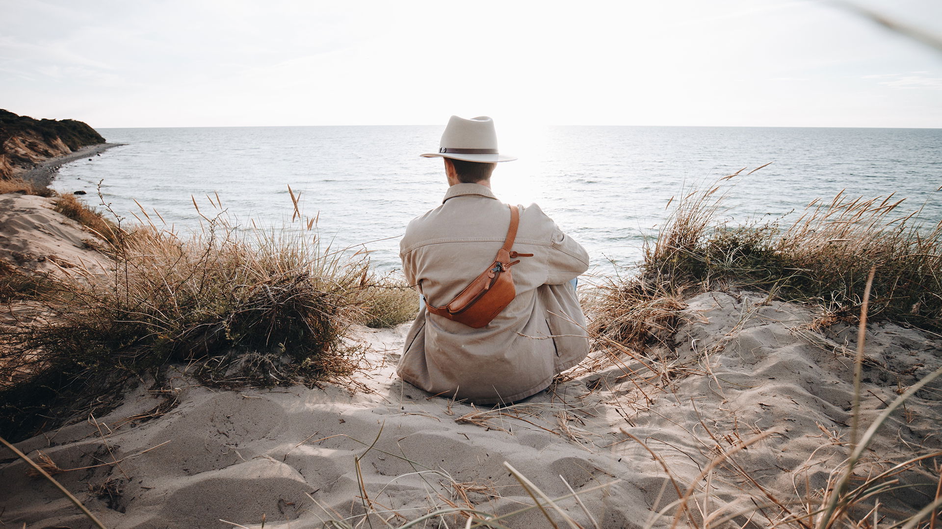 männliches Model am Strand mit einer Herren-Gürteltasche aus Leder.