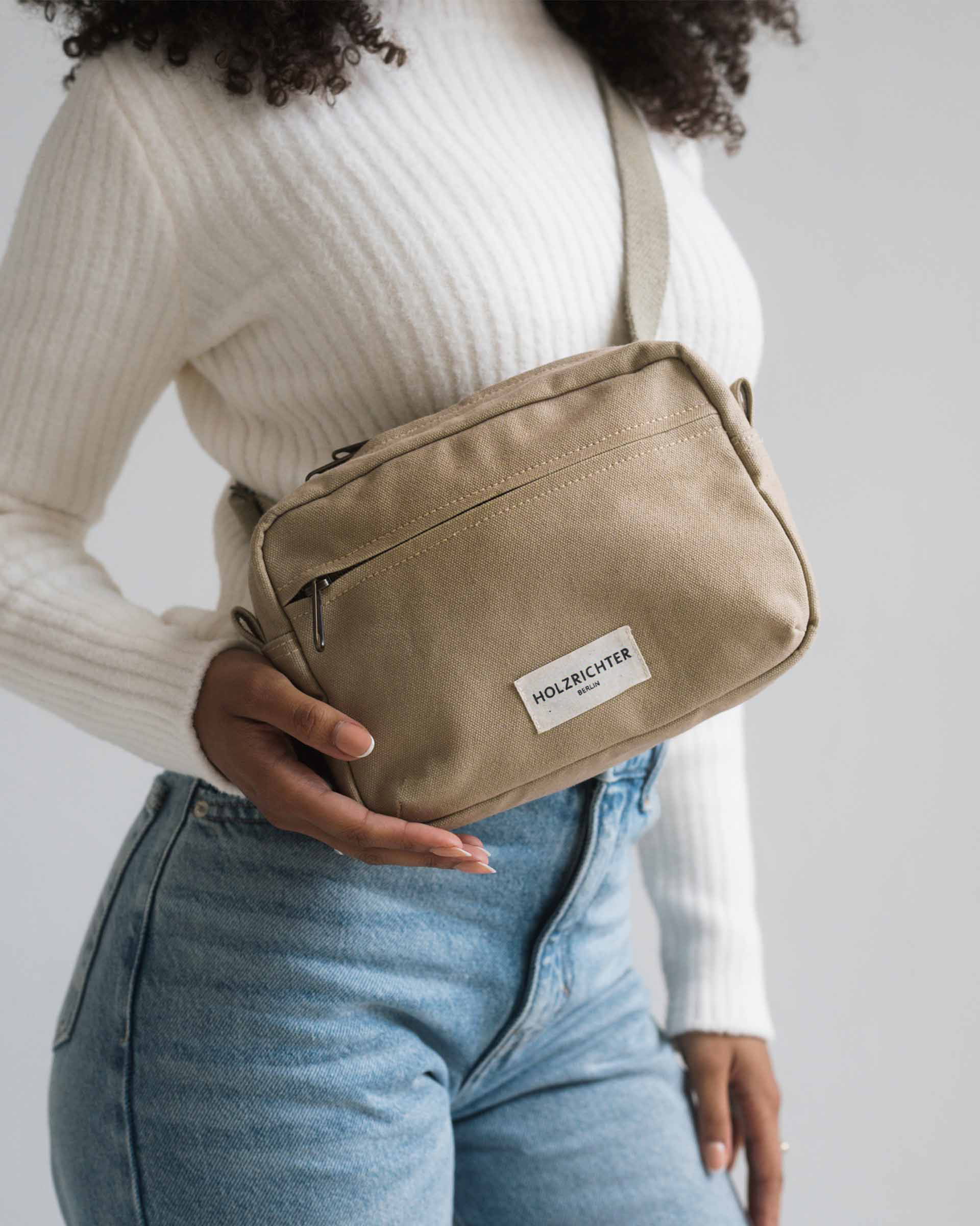 Kompakte beigefarbene Crossbody-Tasche aus Leder mit verstellbarem Schulterriemen und Reißverschluss