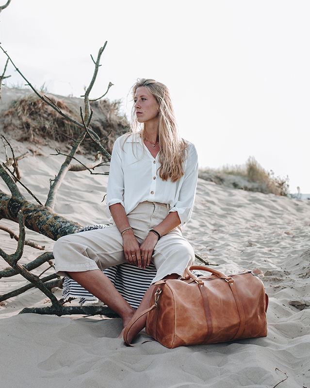 weibliches Model mit einer Leder-Reisetasche für Damen.